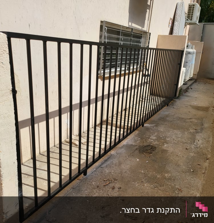גדר מתכת שחורה ליד קיר בטון